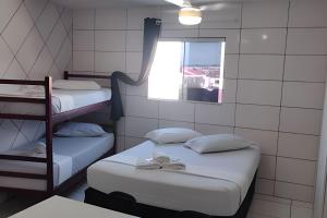 two beds in a small room with a window at Residencial Tia Antonia in Curitiba
