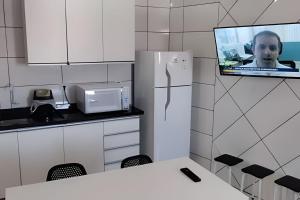 a kitchen with a refrigerator with a tv on the wall at Residencial Tia Antonia in Curitiba