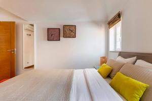 una camera da letto con un letto bianco con cuscini gialli di Tower of Belém Premium Apartments A, B & C a Lisbona