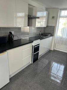 a kitchen with white cabinets and black counter tops at Charming 2 Storey Holiday Villa in Dawlish Warren in Dawlish Warren