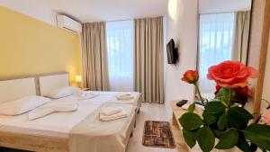 ein Hotelzimmer mit zwei Betten und einer Vase mit Rosen in der Unterkunft Hotel Diana in Eforie Nord