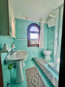 a blue bathroom with a sink and a toilet at Villetta Anna in Golfo Aranci
