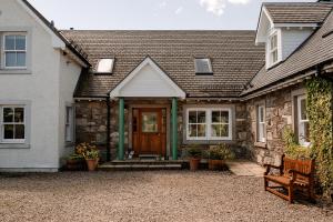 a stone house with a wooden door and a bench at Deanshaugh - Seasgair Lodges in Deanshaugh