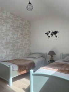 a bedroom with two twin beds and a wall at Entre terre et mer in Val Couesnon