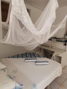 a white bed with a mosquito net above it at La Casa des Lucioles in Saint-Louis