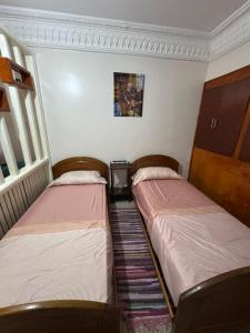 two beds in a small room withermottermottermott at Appartement Atlas, Rue Mouatamid Ibn Abbad, Immeuble Malki, 1er étage, Oujda in Oujda +6 photos