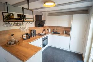 a kitchen with white cabinets and a wooden counter top at Ferienhaus Schlossberg mit Infrarot-Kabine und Stellplatz in Quedlinburg +14 photos