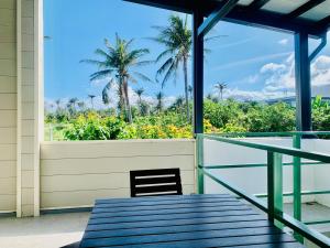 a balcony with a chair and a view of palm trees at The Moment Hostel Dulan in Donghe +40 photos