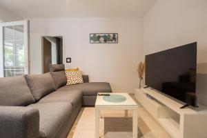 a living room with a couch and a flat screen tv at VILLA MILENKA - Apartmani Gorana in Tučepi