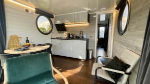 a living room with a table and chairs and a kitchen at Houseboat 18 Nordic in Offingawier