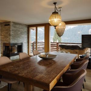 a dining room with a wooden table and a fireplace at Bergwelt Grindelwald Residence in Grindelwald