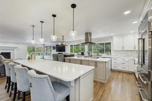 una cocina con armarios blancos y una gran isla con sillas en Poolhouse in the Pines, en Colorado Springs