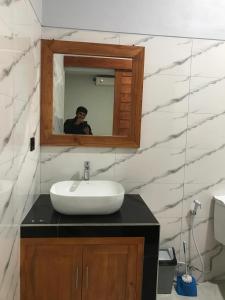 un homme prenant une photo d'un lavabo dans une salle de bains dans l'établissement Rumah Asri Devarastra #1, à Amed