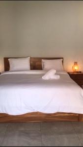 Elle comprend un grand lit avec des draps et des oreillers blancs. dans l'établissement Rumah Asri Devarastra #1, à Amed