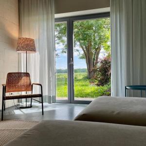 a bedroom with a chair and a large window at Ferienwohnung ZWEI Hof Himmelgrün in Saal
