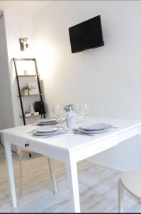 a white dining room table with plates and wine glasses at Studio-parking-wifi-Disney-Val d'Europe 10 mn in Montévrain