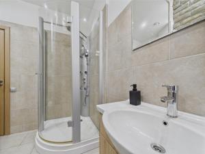 リガにあるRaw and Refined 2BR Old Town Apartmentのシャワーと白い洗面台を備えたバスルーム