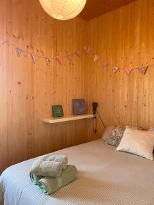 Un dormitorio con una cama en una pared de madera. en El Racó de Baix, en Seva