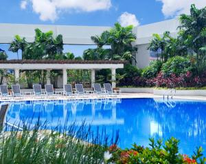 uma piscina com cadeiras e um edifício em Concorde Hotel Shah Alam em Shah Alam