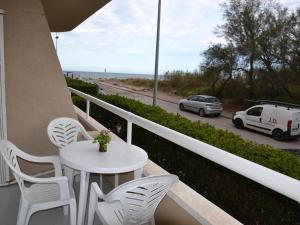 une table et des chaises blanches sur un balcon donnant sur une rue dans l'établissement Apartamento acogedor en la playa con acceso directo al mar y piscina en L'Estartit - ES-323-22, à L'Estartit