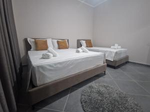 zwei Betten in einem Zimmer mit weißen Laken und Kissen. in der Unterkunft Vila Pulo in Tragjas