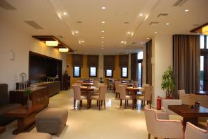 ein Esszimmer mit Tischen, Stühlen und Fenstern in der Unterkunft Agapi Luxury Hotel in Kato Loutraki
