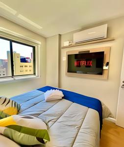 a bedroom with a bed with a tv on the wall at O fenômeno, Apto nobre in Curitiba