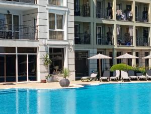 a swimming pool with chairs and umbrellas next to a building at Festa Studio in Pomorie