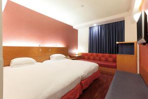 a hotel room with two beds and a television at Hotel Nikko Narita in Narita