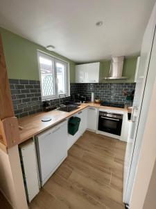 een keuken met witte kasten, een gootsteen en een raam bij Maison cosy avec jardin & parking, proche Disney in Chelles