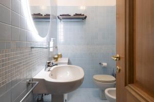 Un baño con azulejos azules, lavabo e inodoro. en Ca' forte residence, en Venecia