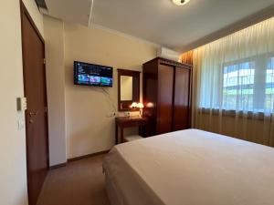 a hotel room with a bed and a television on the wall at Downtown Bansko Luxury Resort in Bansko