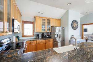 a kitchen with wooden cabinets and a stainless steel refrigerator at Steps to Beach Pool Game Room Aug Weeks Open in Corolla