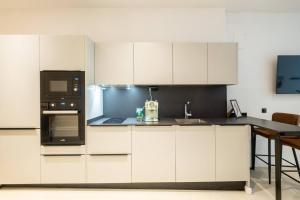 a kitchen with white cabinets and a black appliance at Apt new Mestalla | jacuzzi | billar | ping pong in Valencia +42 photos