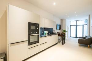 a kitchen with white cabinets and a black appliance at Apt new Mestalla | jacuzzi | billar | ping pong in Valencia