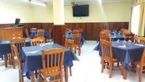 a dining room with blue tables and chairs and a tv at Posada La Bolera in Anero