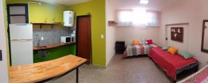a room with a bed and a kitchen with green walls at El Departamentito in Villa Mercedes