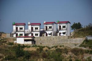 ein großes weißes Gebäude mit roten Dächern auf einem Hügel in der Unterkunft Tathastu Resorts in Tehri-Garhwāl