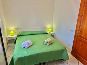two stuffed animals laying on a green bed at Casa Marmolada - San Teodoro in San Teodoro
