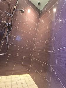 a bathroom with a shower with brown tiles at 25 min du Puy du F, en sortant de Cholet in Le May-sur-Èvre