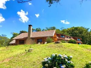 a house on top of a grassy hill at Log Cabin - Monte Verde in Camanducaia