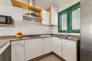 a kitchen with white cabinets and a sink at Apartamento BANDAMA nº 5, recién renovado, newly renovated bungalow, Los Pocillos, Tías in Puerto del Carmen +3 photos
