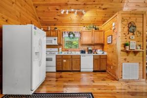 a kitchen with a white refrigerator and wooden cabinets at Cupids Hideaway Gatlinburg in Sevierville