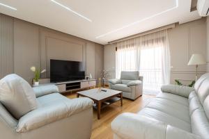 a living room with white furniture and a flat screen tv at Apartments Dream in Tivat