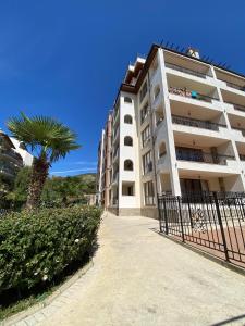 a building with a palm tree next to a fence at Marina Park OLIWIA in Sveti Vlas