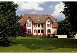 a large house on a grassy field with trees at Villa Knobelsdorff in Pasewalk
