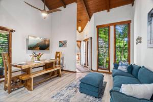 a living room with a table and a blue couch at Tropical Treehouse Near the Beach in Koloa
