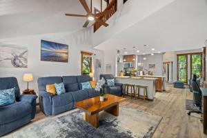 a living room with blue couches and a table at Tropical Treehouse Near the Beach in Koloa