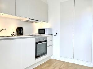 a white kitchen with white cabinets and a microwave at Convenient Apartment for 2 in Aarhus