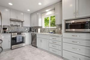 a kitchen with white cabinets and stainless steel appliances at Trendy Getaway - Hot Tub - Putt Putt - Games in Long Beach
